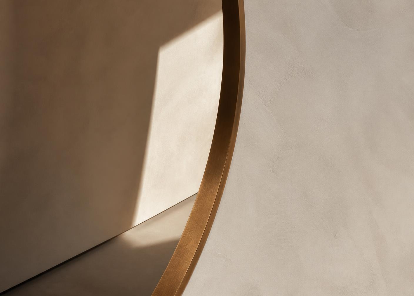 Light falling across a curved plaster wall with bronze reveal